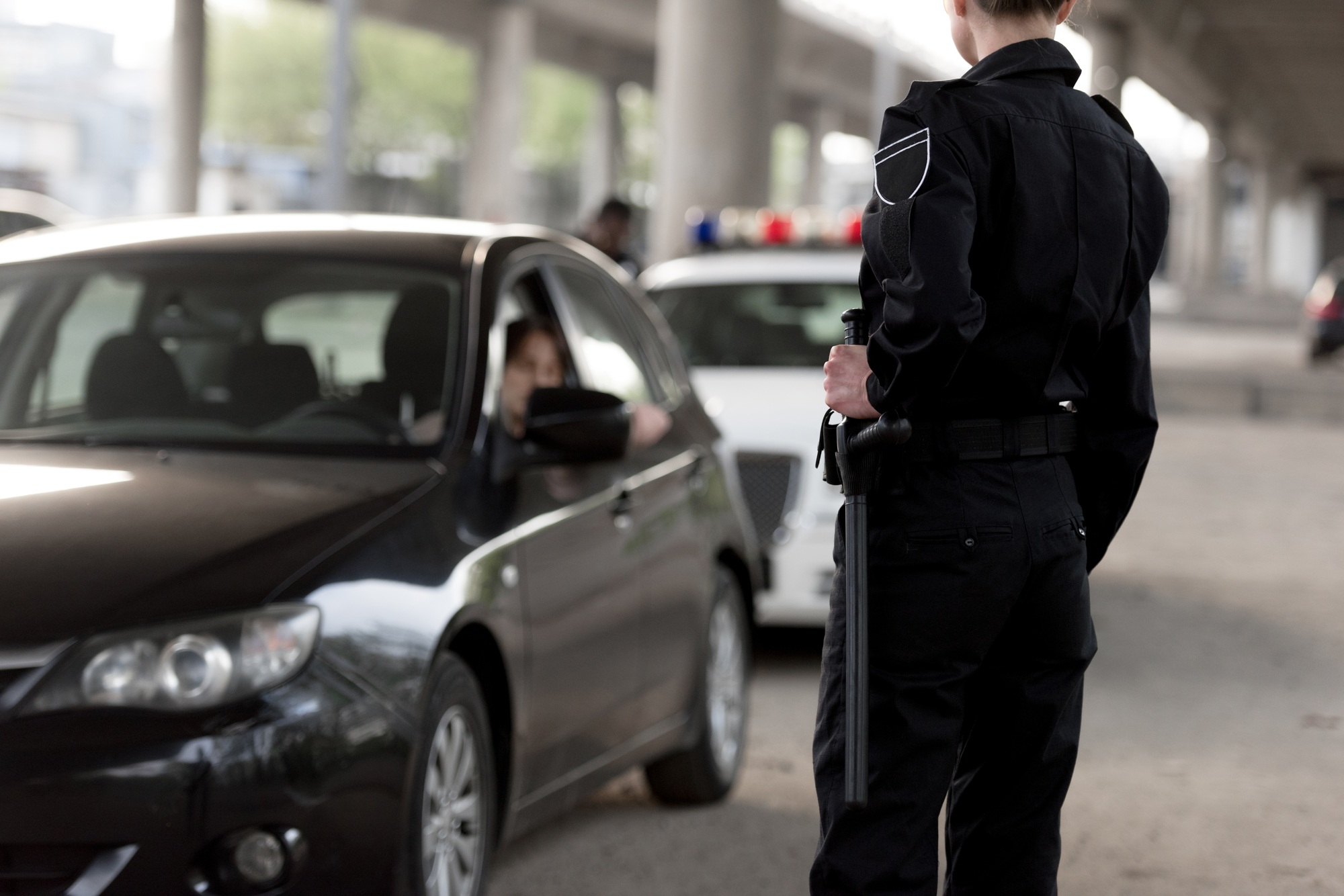 cropped shot of policewoman holding truncheon and stopped car
