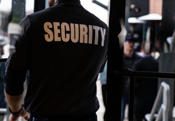 Rear view of a security guard in uniform patrolling in a commercial mall