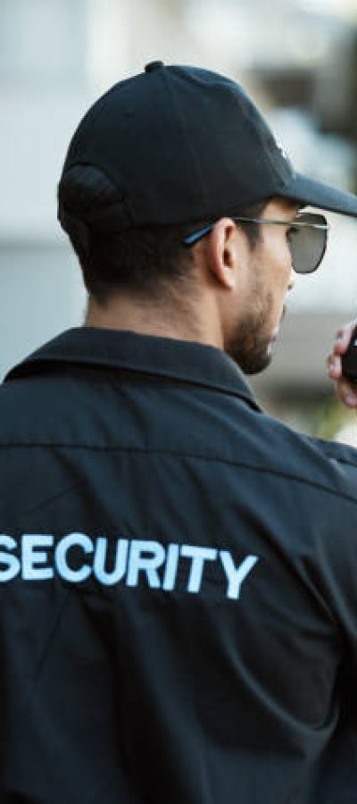 Radio, man and a security guard or safety officer outdoor on a city road for communication. Back of a person with a walkie talkie on urban street to report crime for investigation and surveillance